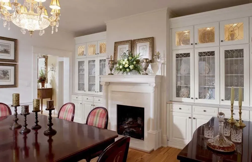 Elegant dining room with white fireplace, built-in cabinets, and a dark wood table under a chandelier
