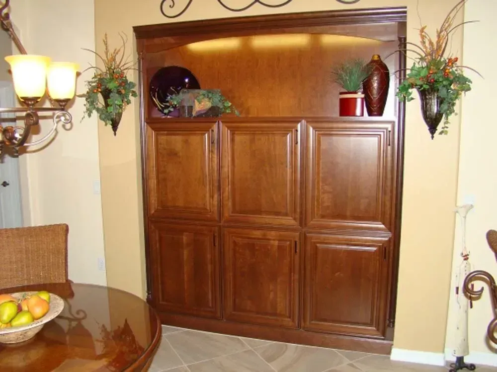 Wooden cabinet with decorative plants and pottery in a warmly lit dining room