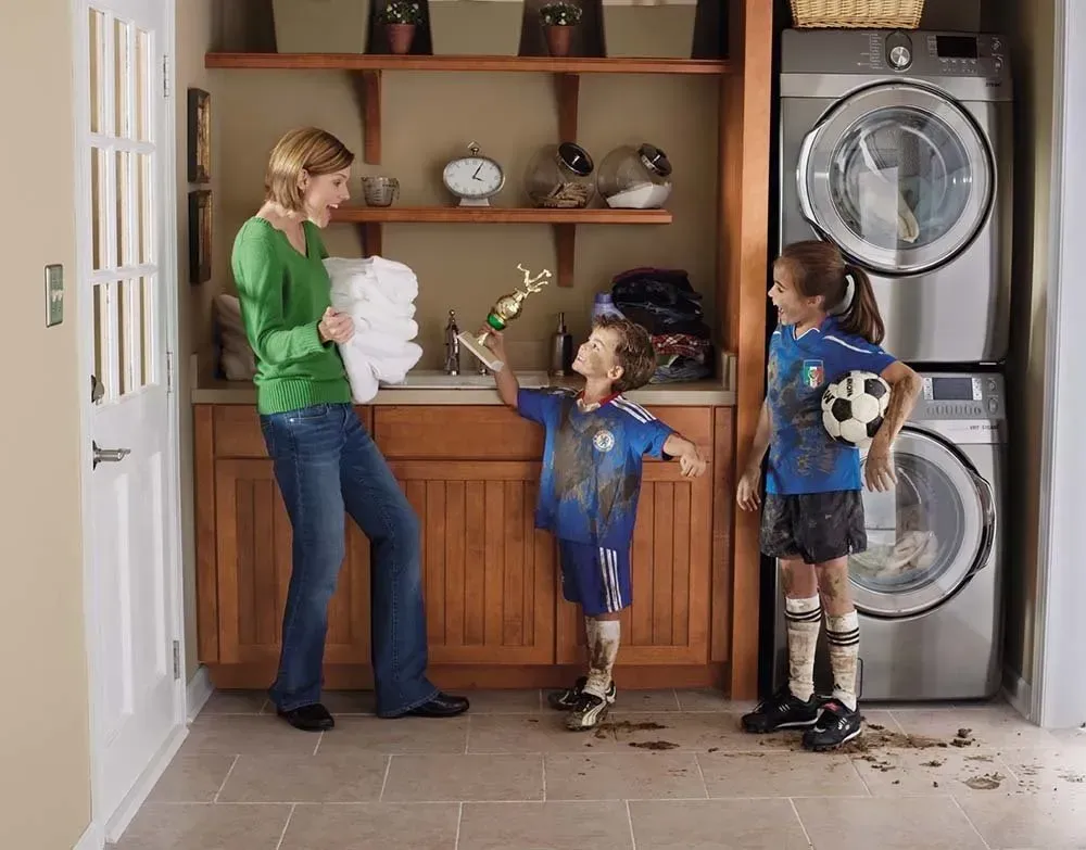 Mother and two children in a kitchen with laundry and a dog by the washer and dryer