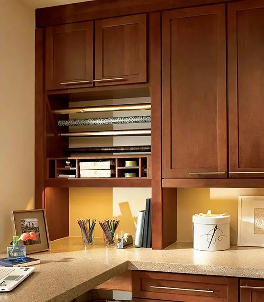 Wooden office cabinets with shelves, desk accessories, and warm under-cabinet lighting.
