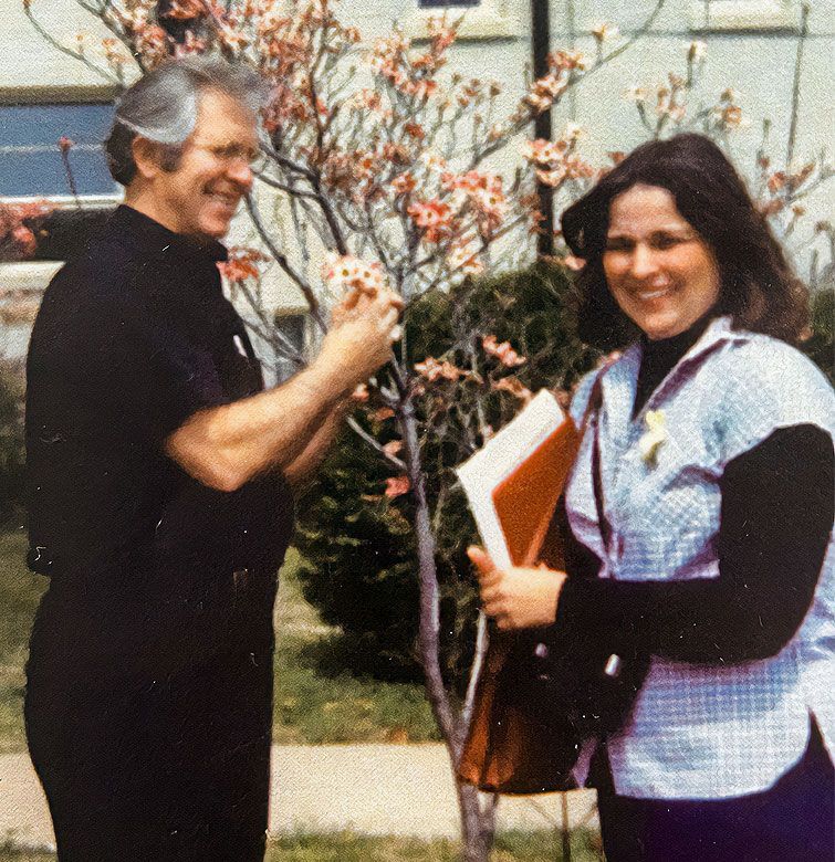 A man and a woman are standing next to each other in front of a tree.