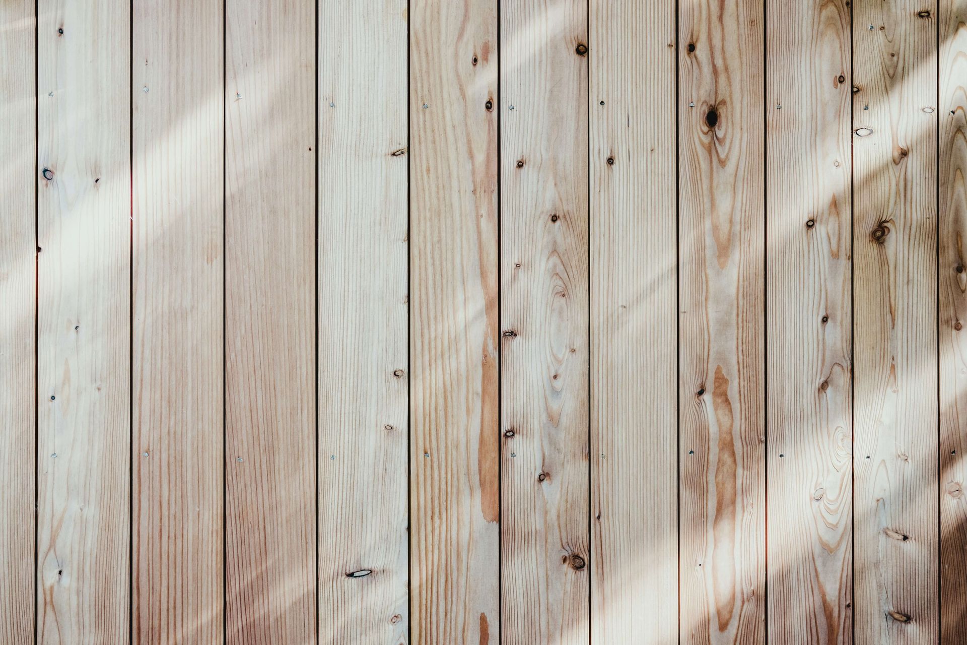 A close up of a wooden fence with the sun shining through it.