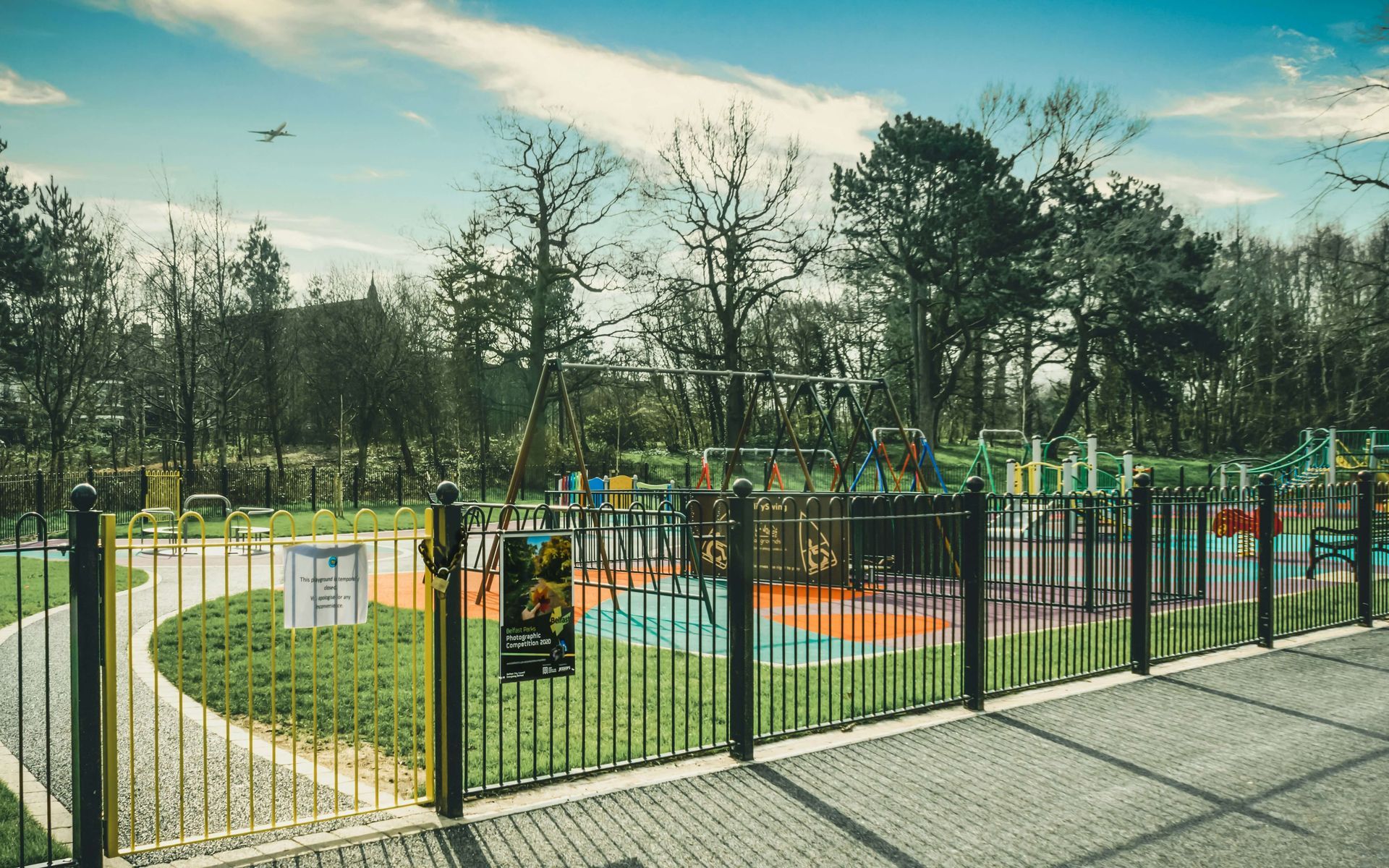A fence surrounds a playground in a park.