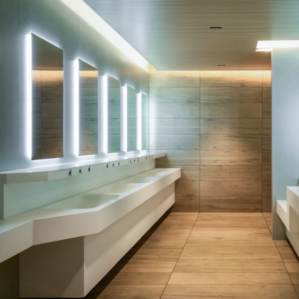 Modern bathroom with white sinks, mirrors, and warm wood-toned wall.