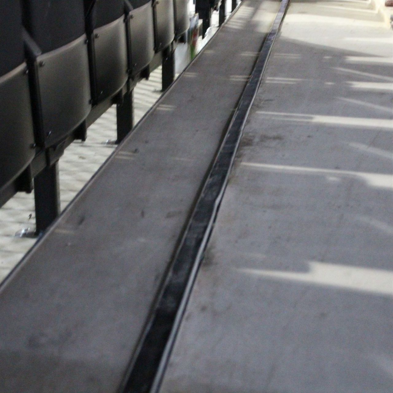 Black drain on a concrete surface next to stadium seating.