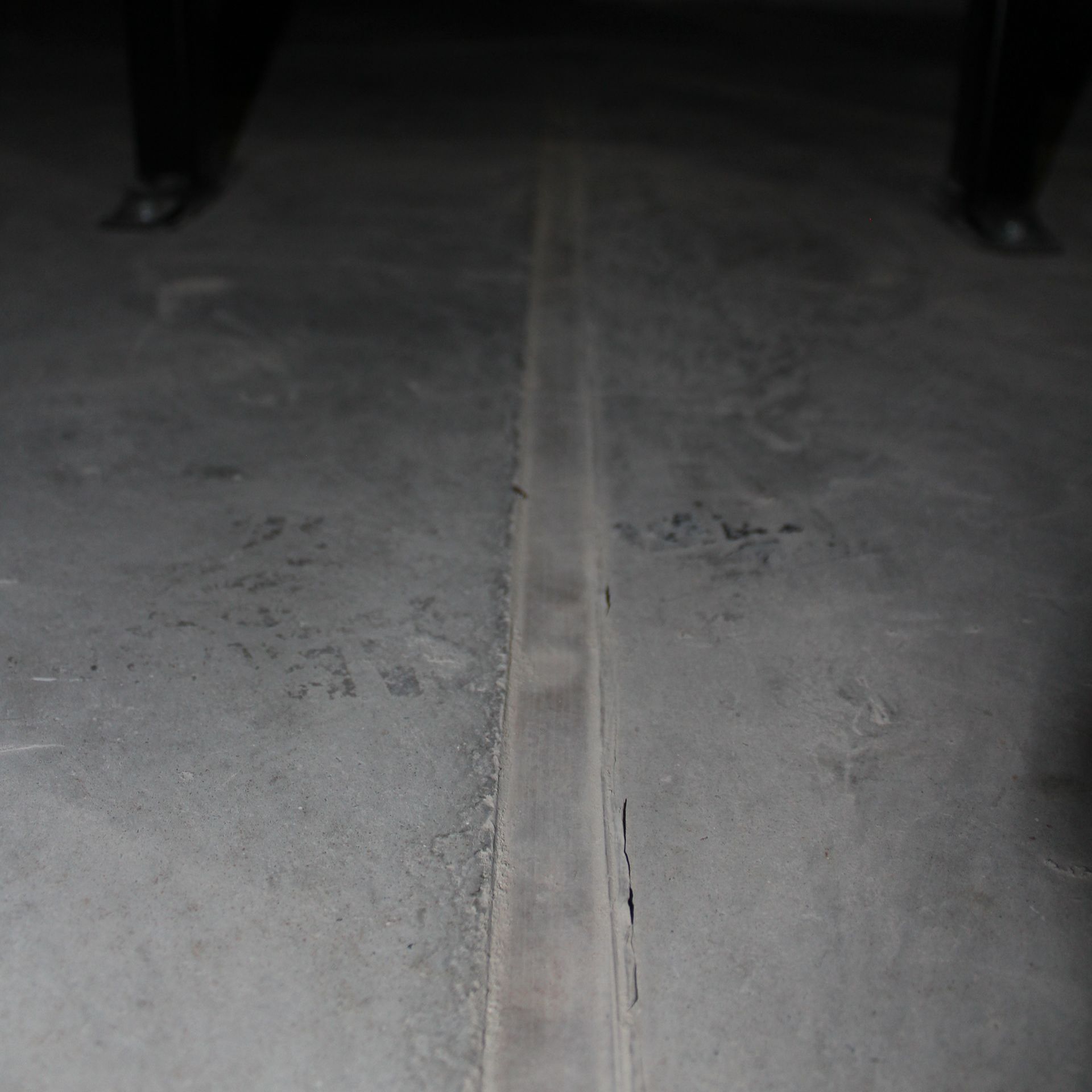 Concrete floor with a seam running down the center, legs in the background.
