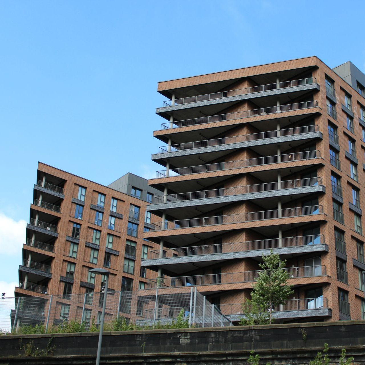 Brick apartment buildings with balconies against a blue sky.