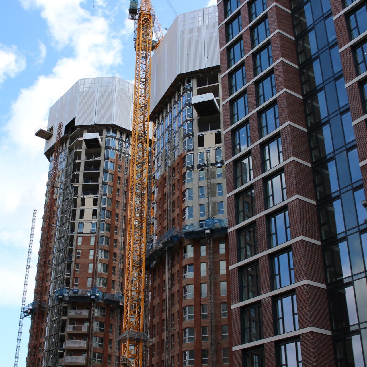 Construction of tall brick buildings, with cranes against a blue sky.