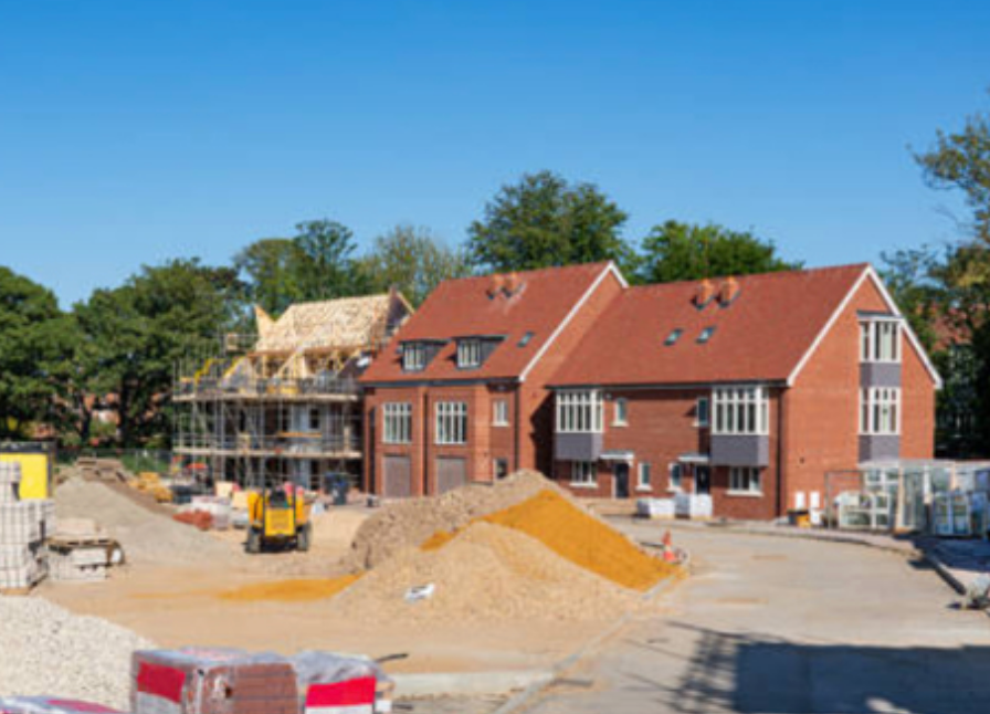 Construction site with new brick buildings under construction; bright sky.