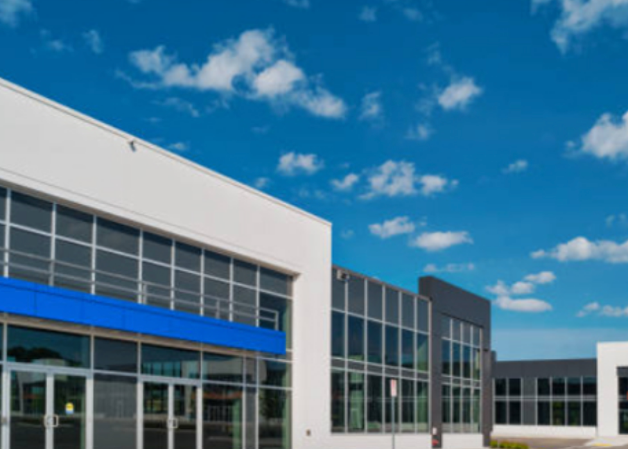 Modern commercial building with large windows, blue accents, and blue sky.