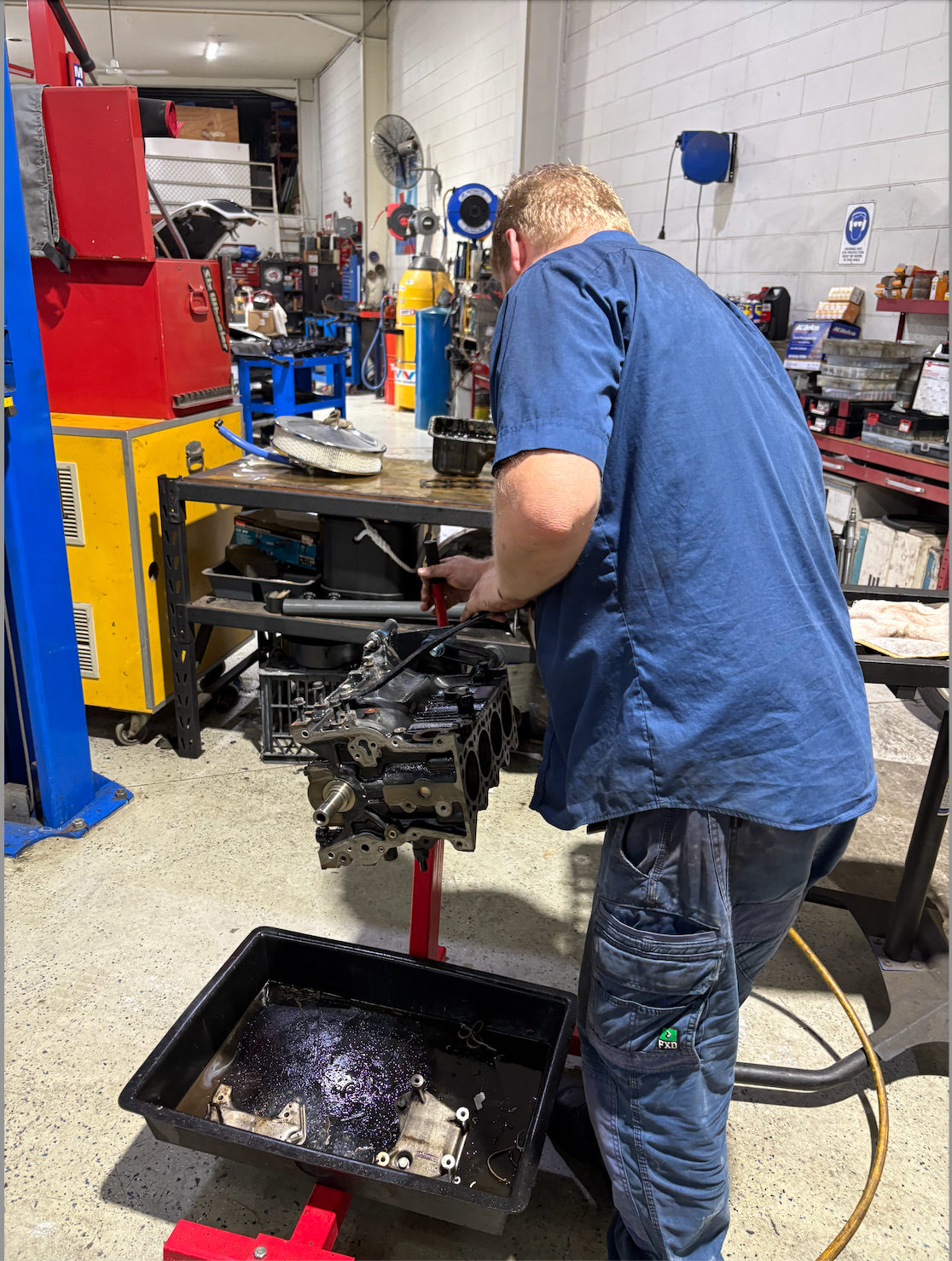A Man Is Working on The Engine of A Car — Monypenny Mechanical in Bungalow, QLD