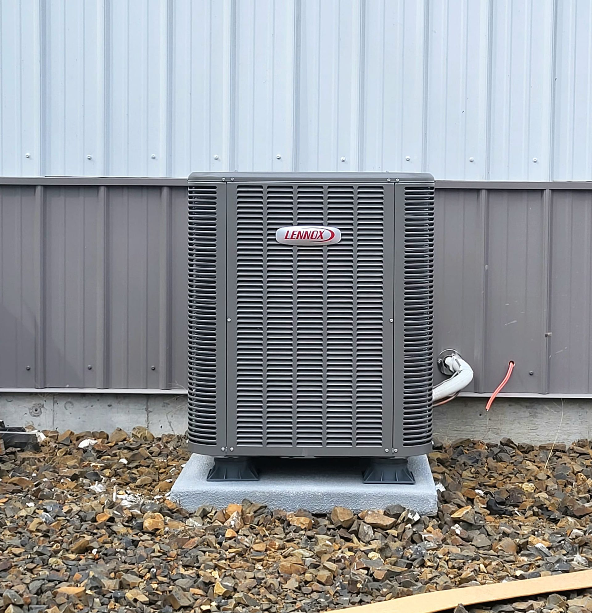 A small air conditioner is sitting outside of a wooden building.
