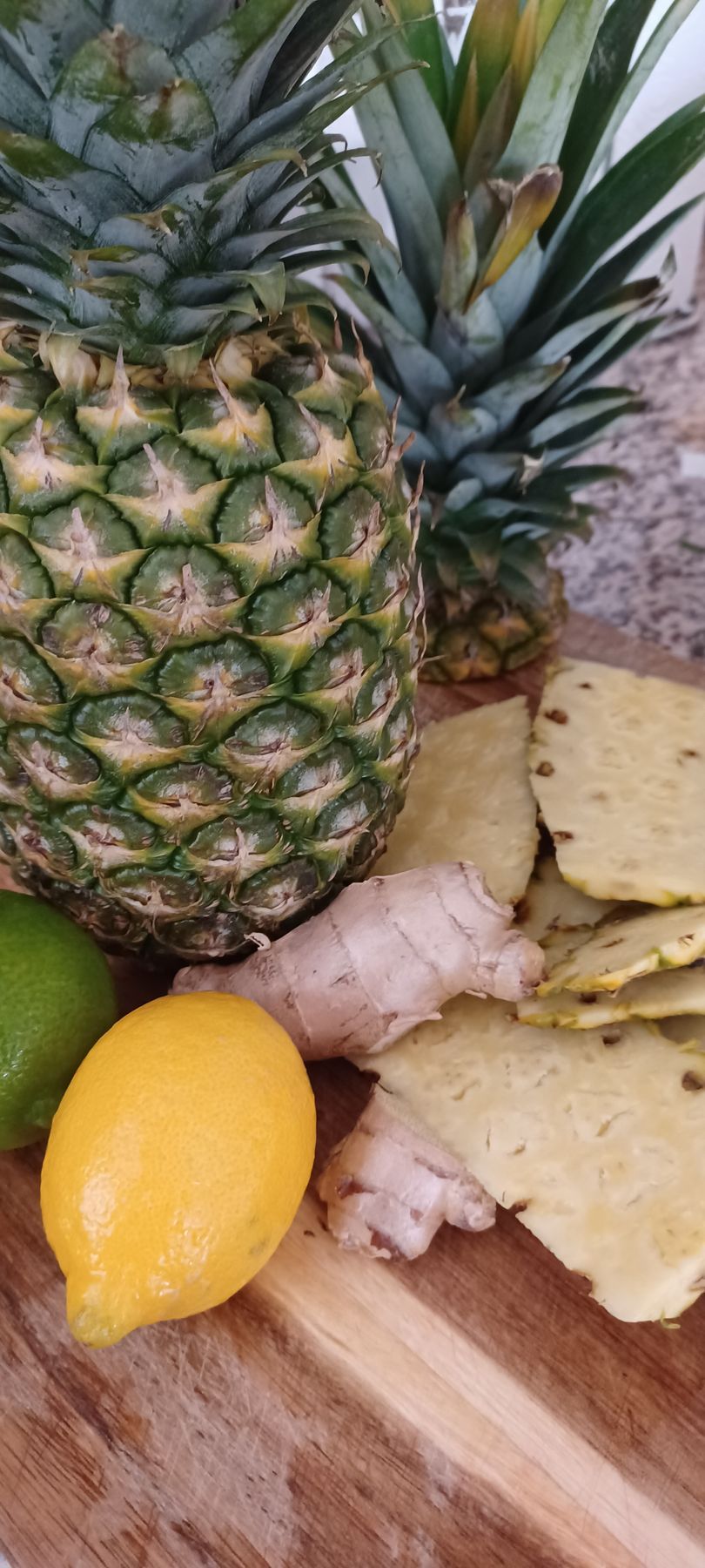 Bottles of Pineapple Ginger Cold Pressed Juice. Clear bottles, yellow liquid, black lids, labels.