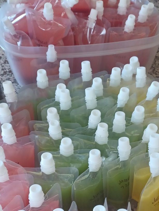 A container and many pouches filled with different colored liquids; pink, green, and yellow.