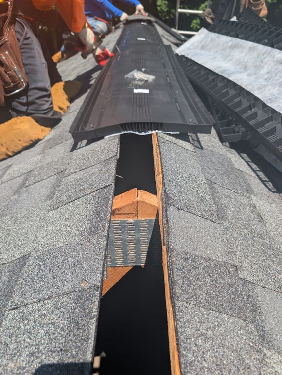 Gloved worker installing terracotta roof tiles on a sloped roof