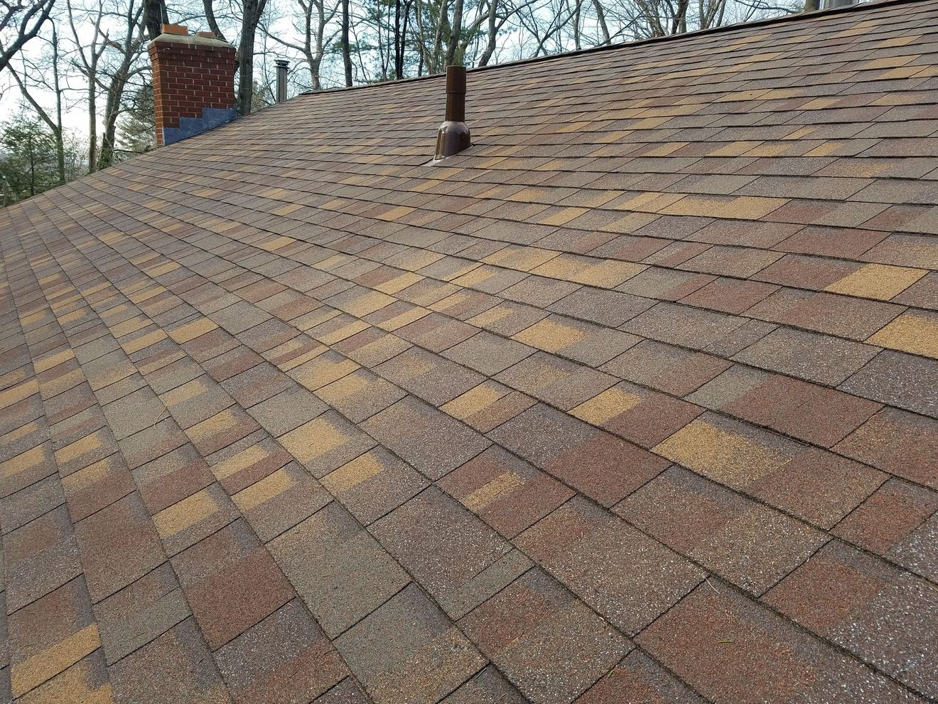 Close-up of dark roof tiles with sunlight reflecting on the sloped roofline