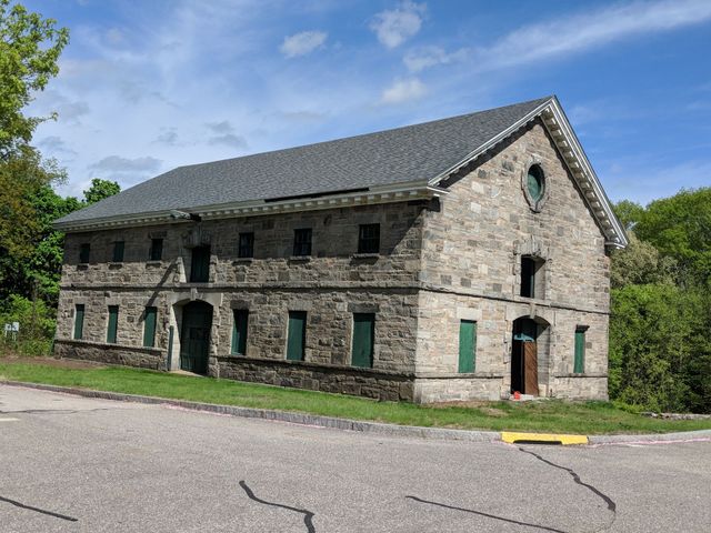 Two red brick chimneys on a dark gray shingled roof under a light stucco wall