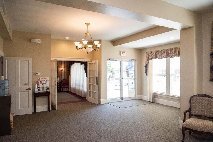 Interior of a building with carpet, doors, and a chandelier; possibly a waiting area.
