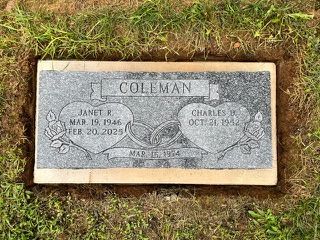 A gray, rectangular grave marker for the Coleman family, featuring two hearts, wedding rings, and floral carvings.
