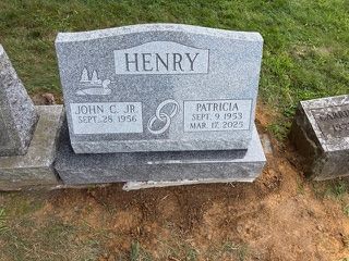 A grey granite headstone for John C. Henry Jr. and Patricia Henry, featuring their names, birth, and death dates.