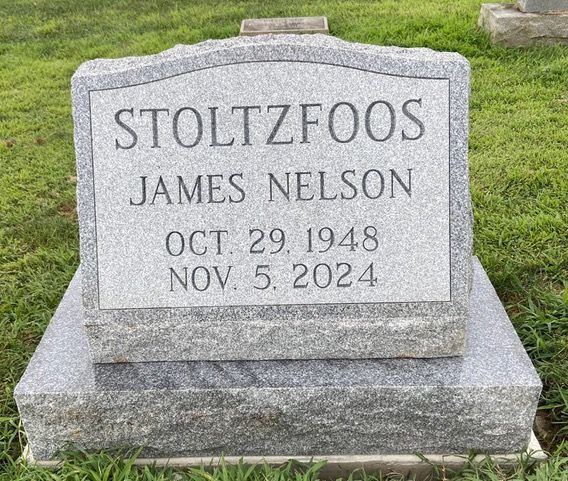 A gray granite headstone for James Nelson Stoltzfoos, born Oct. 29, 1948, and died Nov. 5, 2024, set in a grassy cemetery.