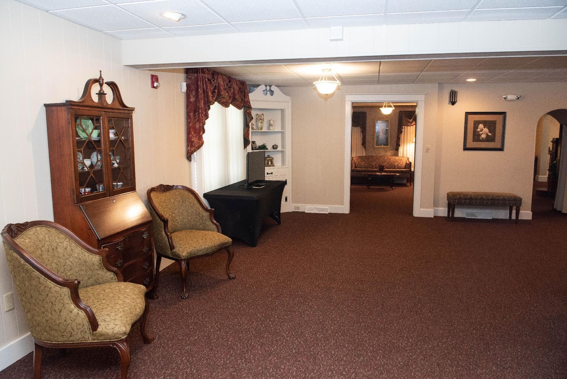 Reception room with chairs, a cabinet, and an open doorway leading to a seating area.