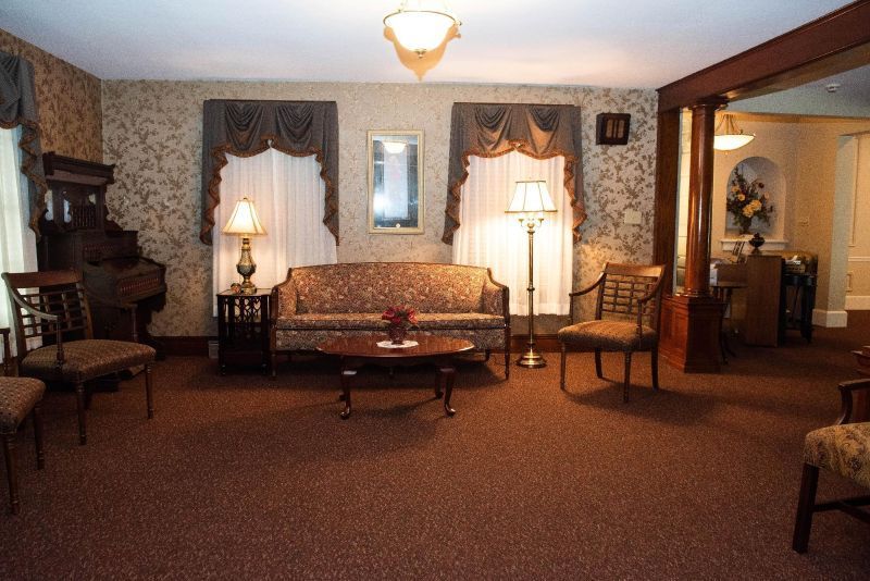 Living room with floral wallpaper, sofa, chairs, lamps, and a small table.
