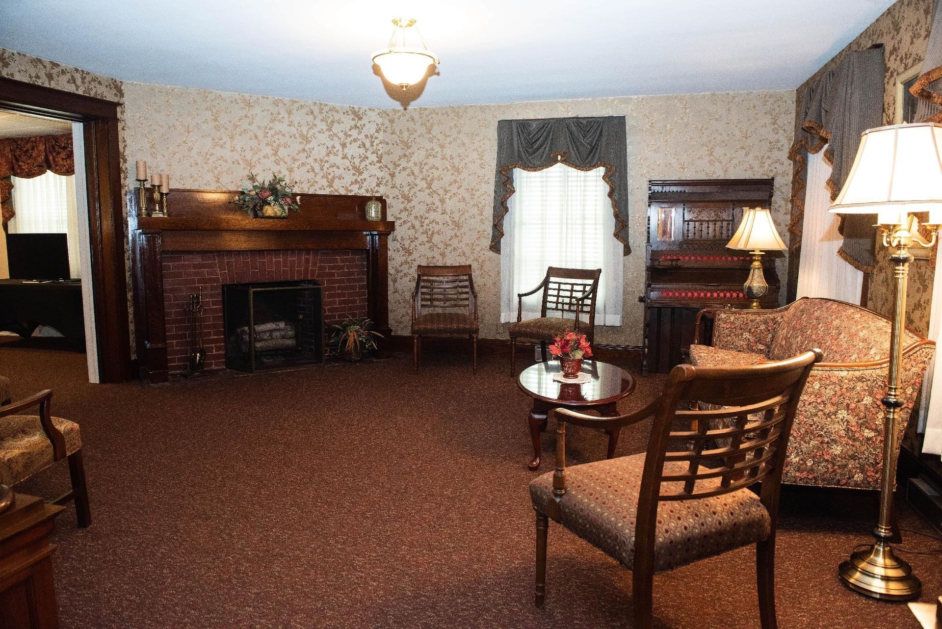Formal living room with fireplace, ornate furniture, and patterned wallpaper.