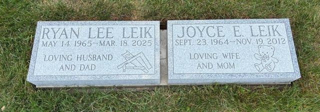 Two side-by-side grey granite grave markers for Ryan Lee Leik (1965–2025) and Joyce E. Leik (1964–2012) set in grass.