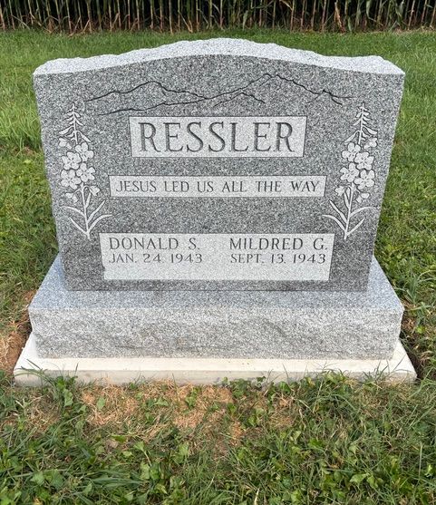 A gray granite gravestone for the Ressler family, featuring floral engravings and the inscription