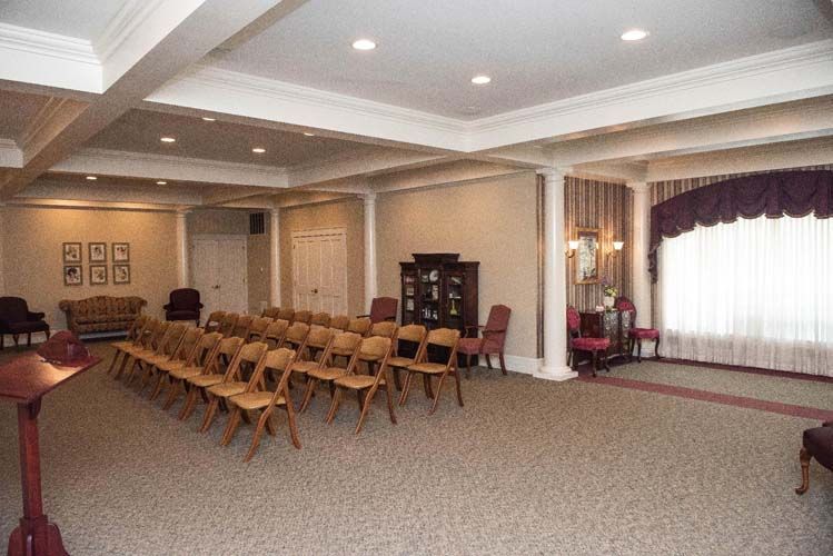 A funeral home chapel with rows of chairs, columns, and a podium.