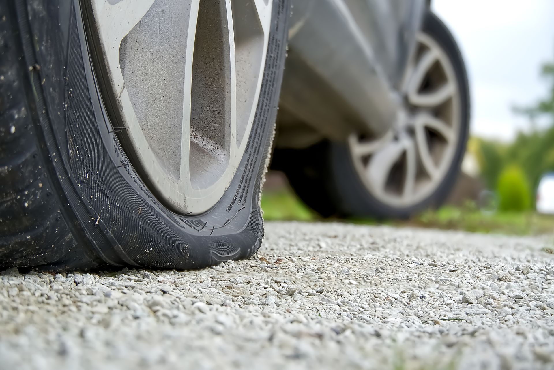 Flat tire on a car parked on a roadside, close-up of the damaged wheel.