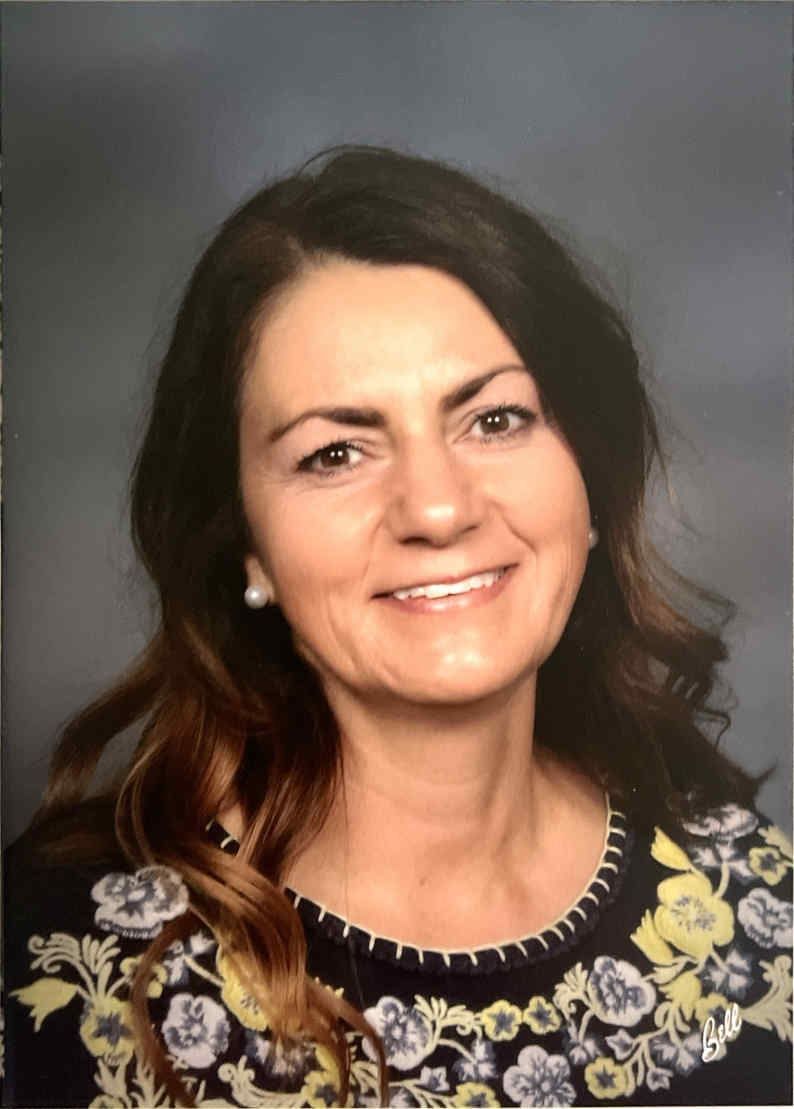 A woman, Heidi King, in a floral shirt is smiling for the camera.