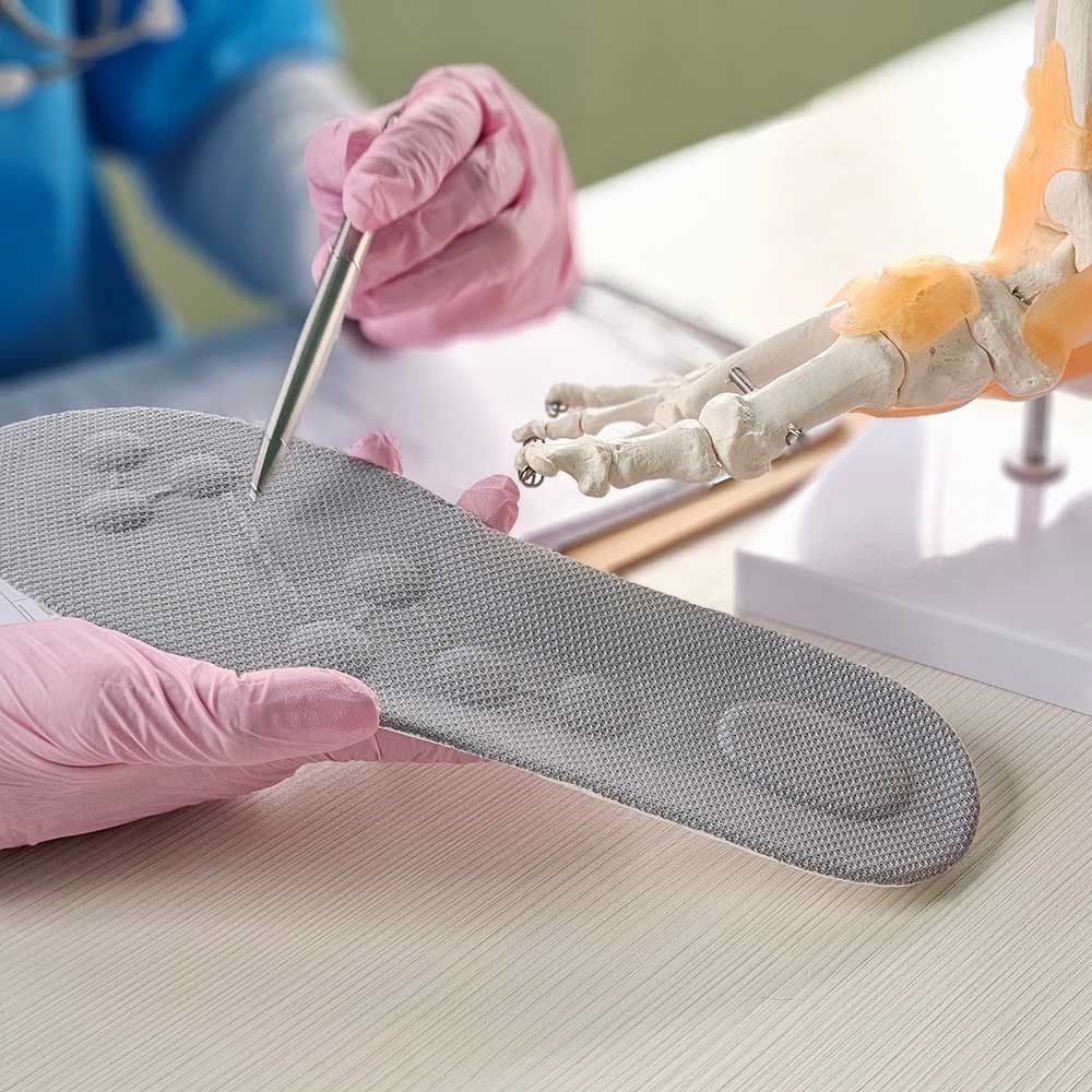 A foot doctor installing a custom orthopedic insole in the Torrington, CT area