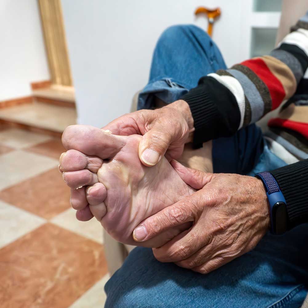 Senior man massaging his injured foot against pain while waiting to see a foot doctor