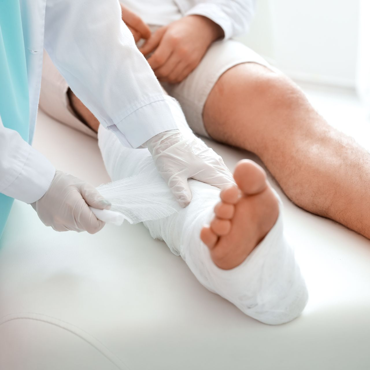 Medical professional bandaging a patient's foot and ankle on an exam table