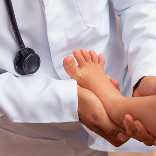 A foot doctor holding a baby’s feet during a medical exam