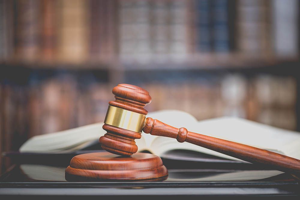 A wooden judge 's gavel is sitting on top of a table next to an open book.