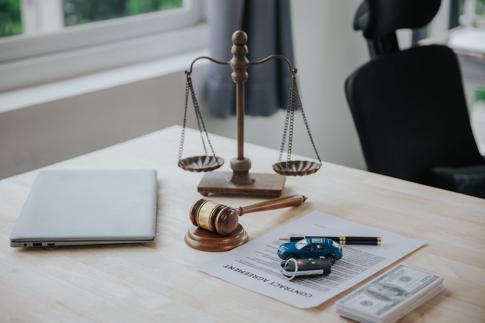 Law office desk with scales of justice, gavel, contract, toy car, and calculator