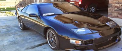 Black sports coupe parked in a driveway, with a red car in the background. | A-Tech Auto Repair