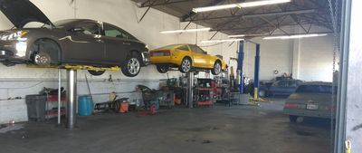 Auto shop with two cars lifted on hoists and another car parked inside. | A-Tech Auto Repair