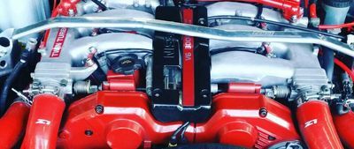 Close-up of a red and silver car engine with visible intake pipes and engine covers | A-Tech Auto Repair