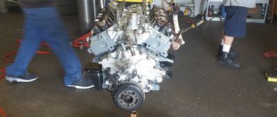 Engine or transmission on floor, with people standing around in a garage or workshop | A-Tech Auto Repair