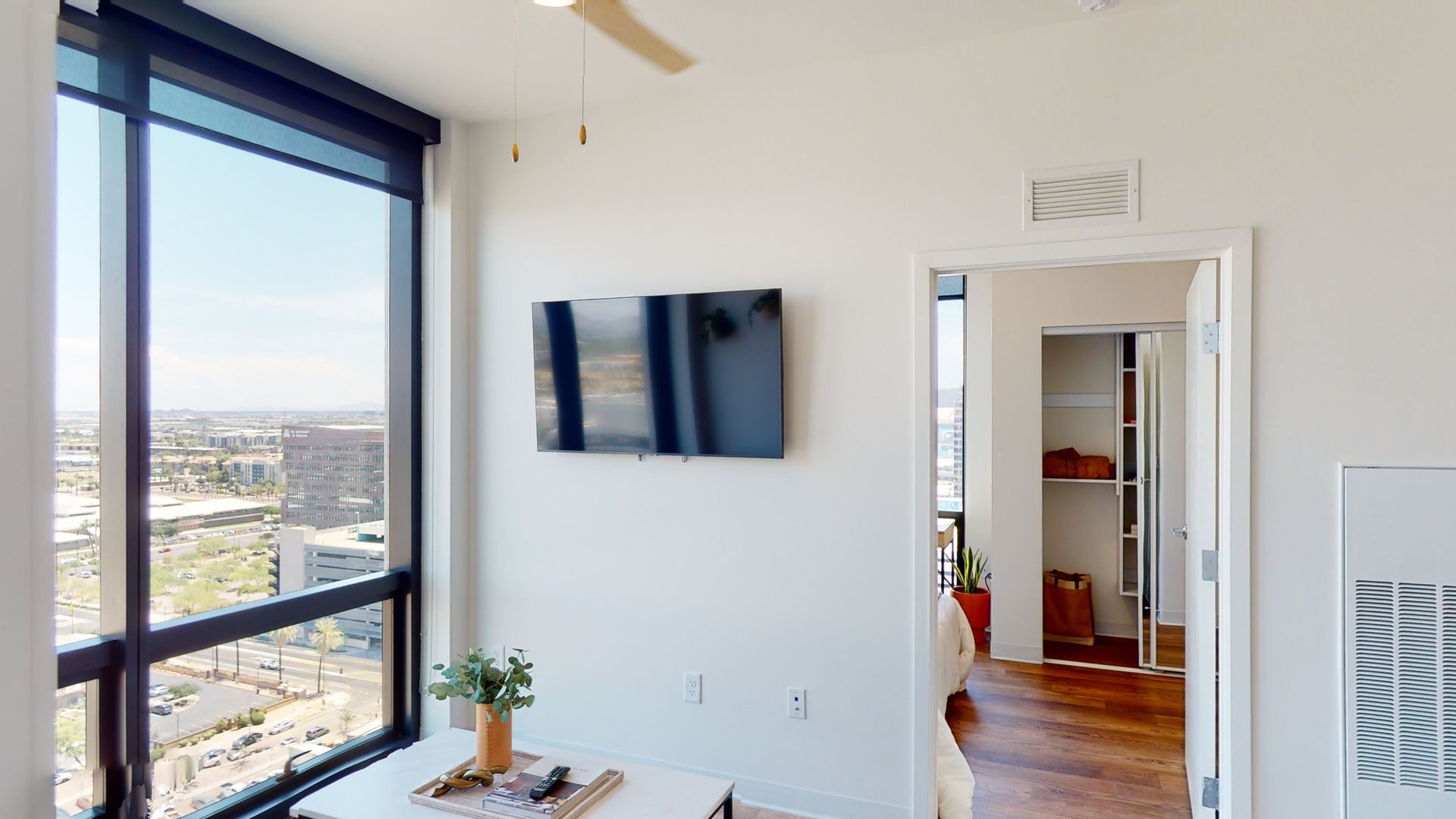 A living room with a large window and a ceiling fan.