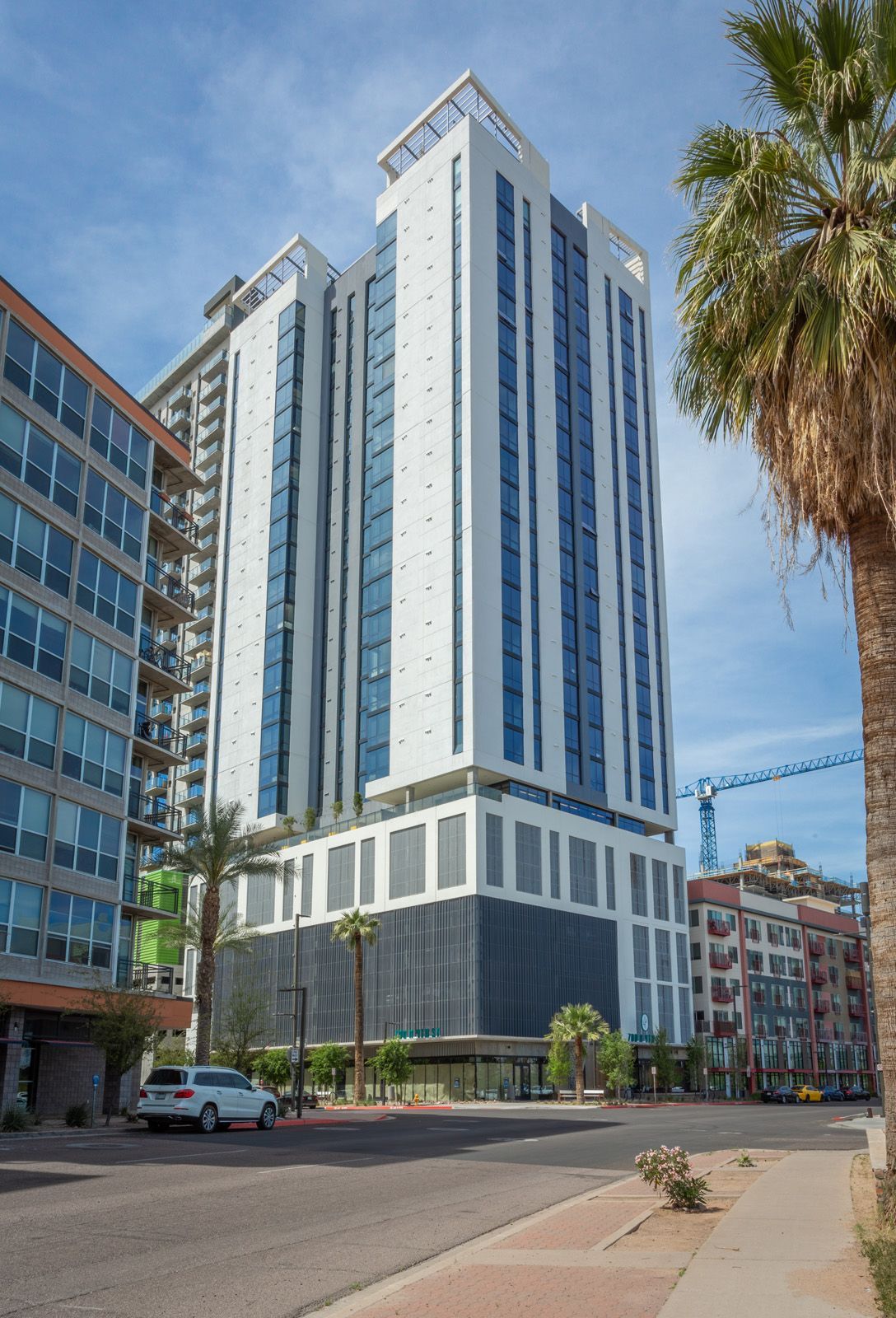 A tall building with a lot of windows is in the middle of a city.