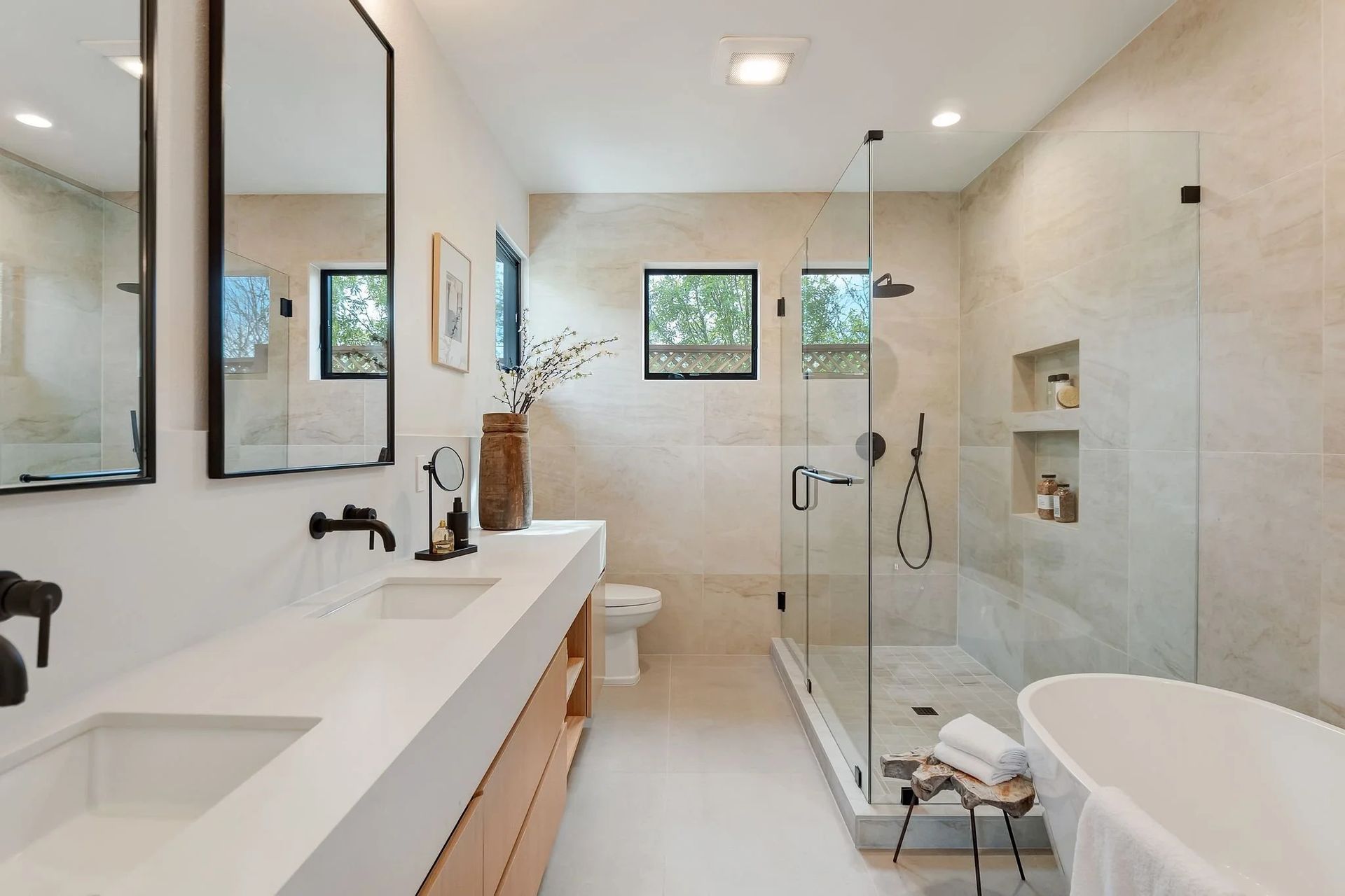 Modern bathroom with double sinks, glass shower, and freestanding tub.