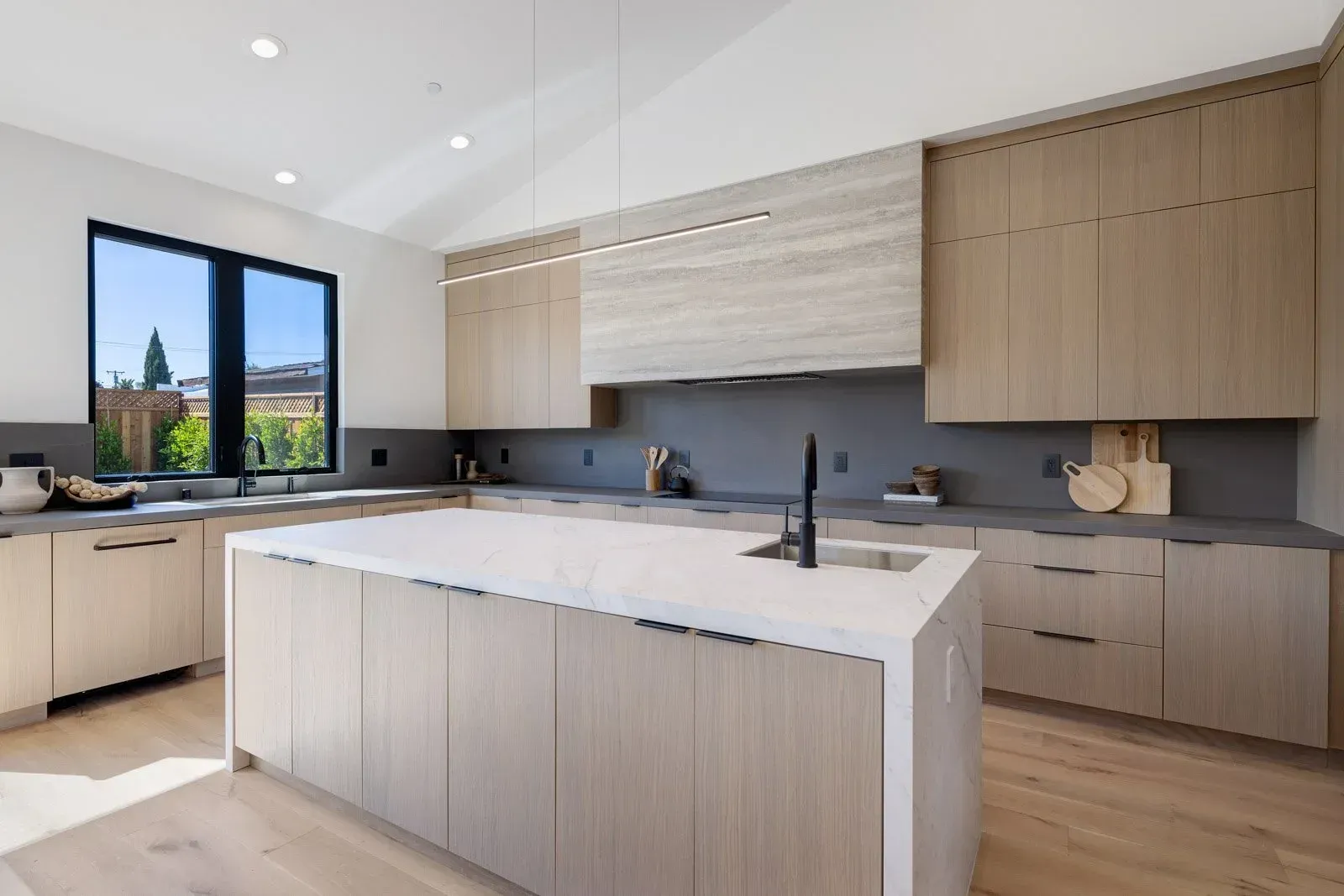 Modern kitchen with light wood cabinets, island, and countertop. 