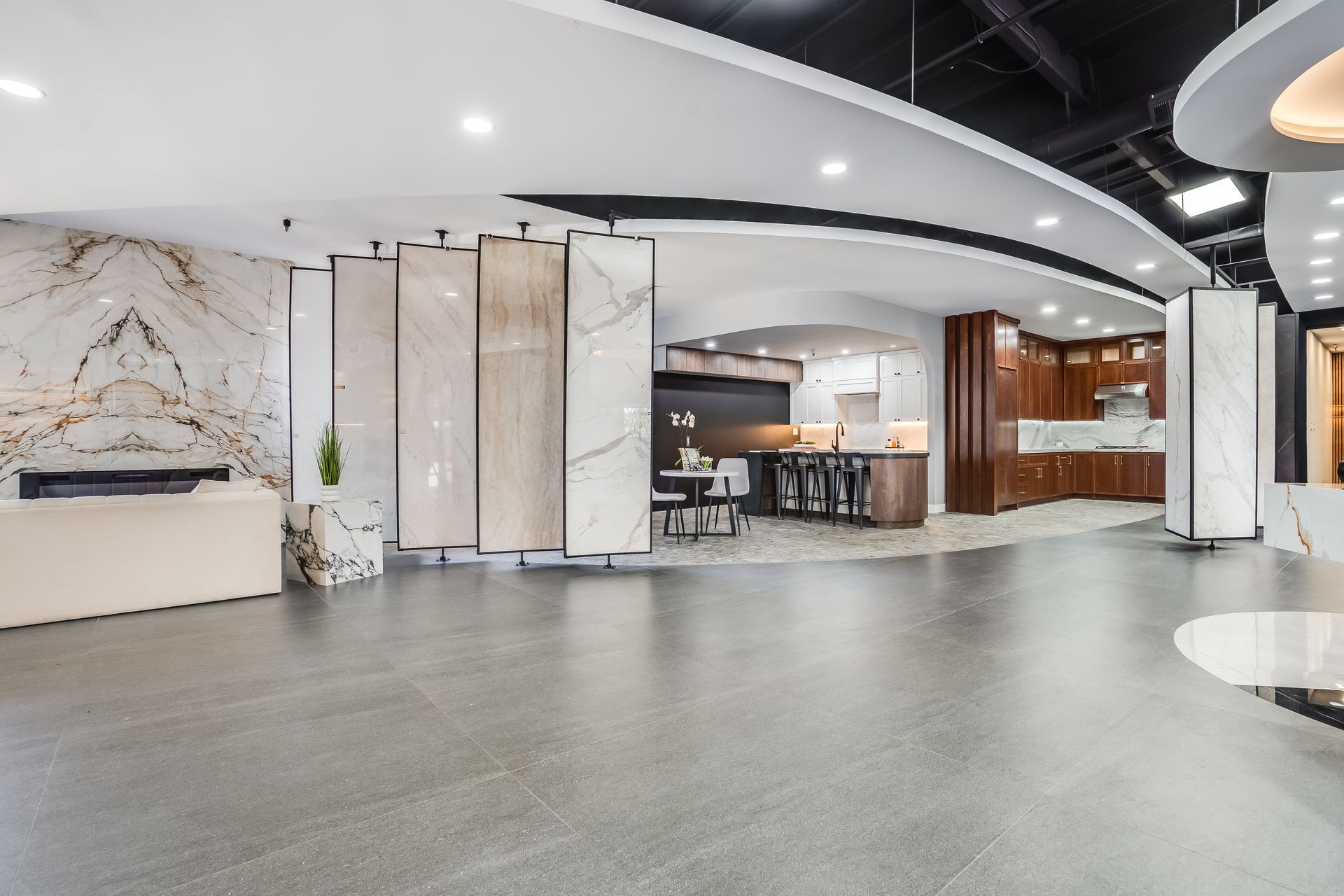 Interior showroom with tile displays, kitchen samples, and a spacious gray floor.