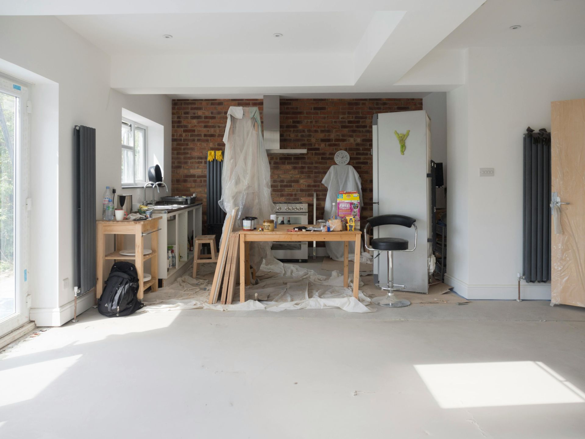 Kitchen under renovation with exposed brick wall and construction materials.