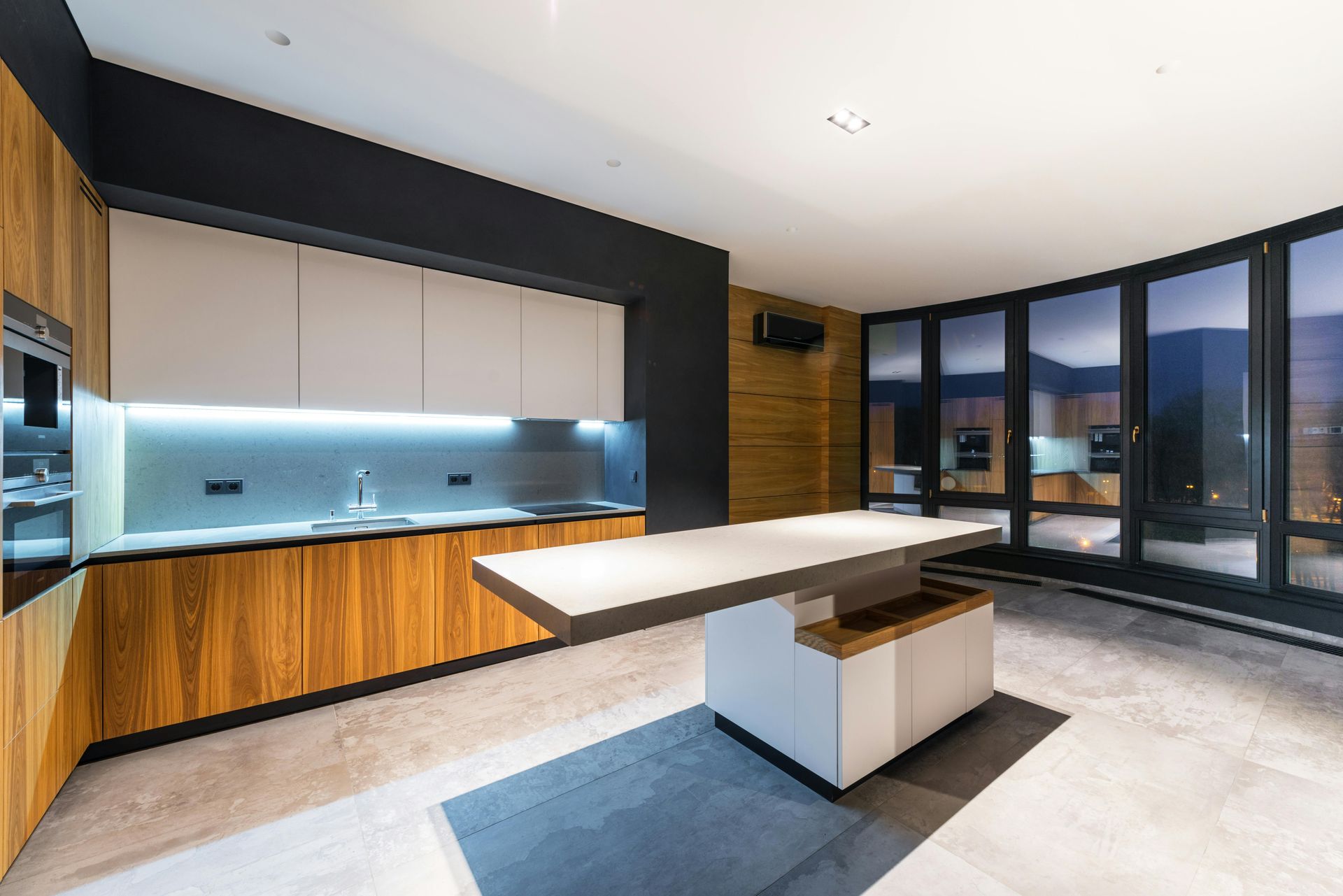 Modern kitchen with wooden cabinets, black wall, island, and floor-to-ceiling windows.